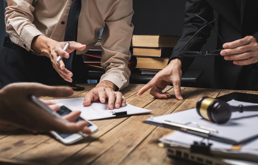 A group of business lawyers collaborating on legal matters in a courtroom to assist their client.