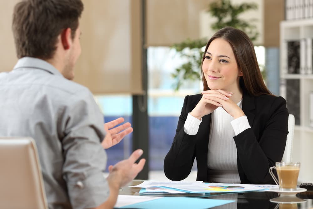 Female lawyer attentively listening to a client speaking in an office setting.