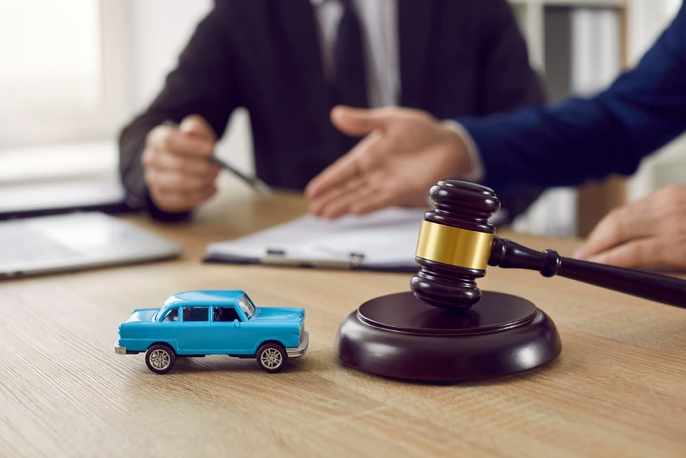 Legal consultation for car accident case with judge's gavel and toy car.
