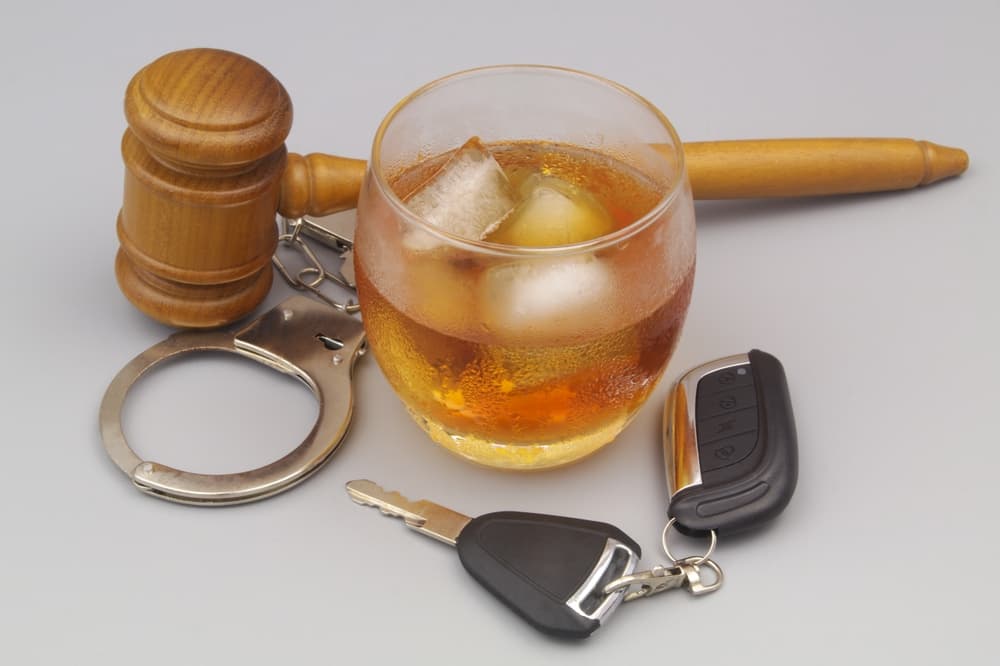 A drink with ice, handcuffs, gavel, and car keys suggesting DUI consequences.