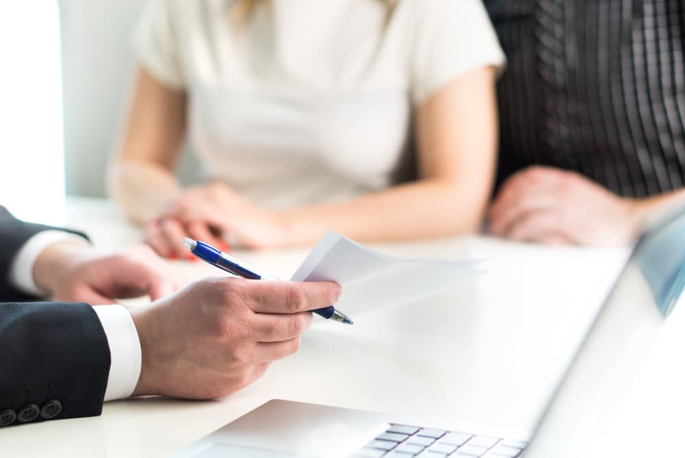 Individuals reviewing documents, negotiating terms for a fair settlement at a desk.