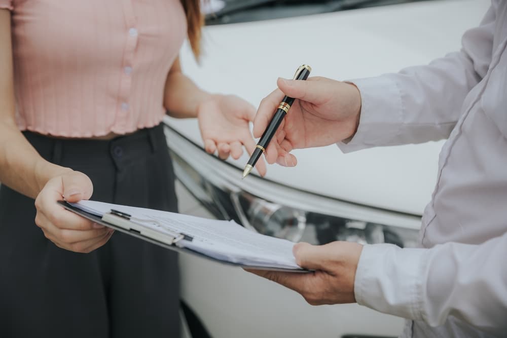 An insurance representative evaluates a vehicle's damage and processes the necessary paperwork for a claim following an accident.