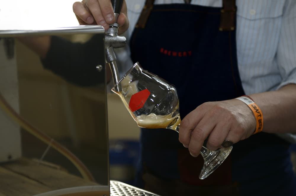 A bartender skillfully fills a glass with frothy draught beer.